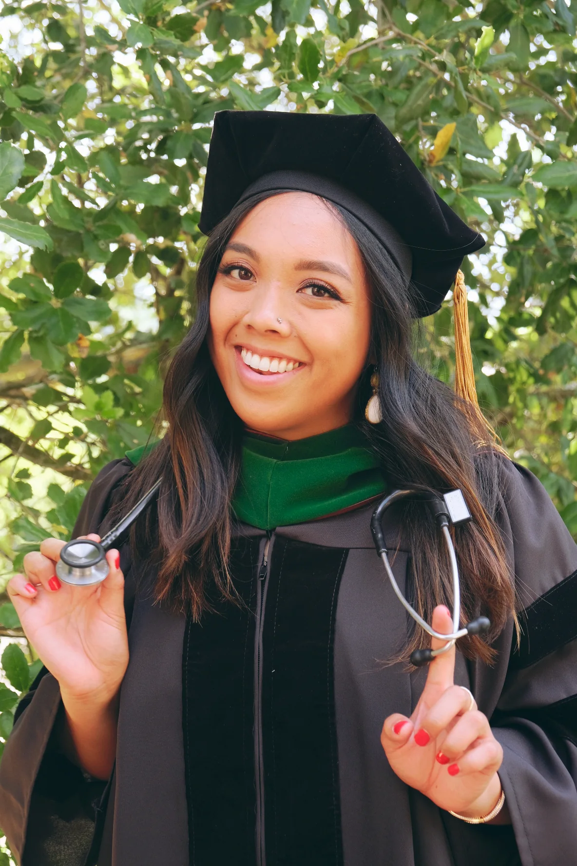Dr. Lexi Gonzales in her doctoral cap and gown, holding a stethoscope